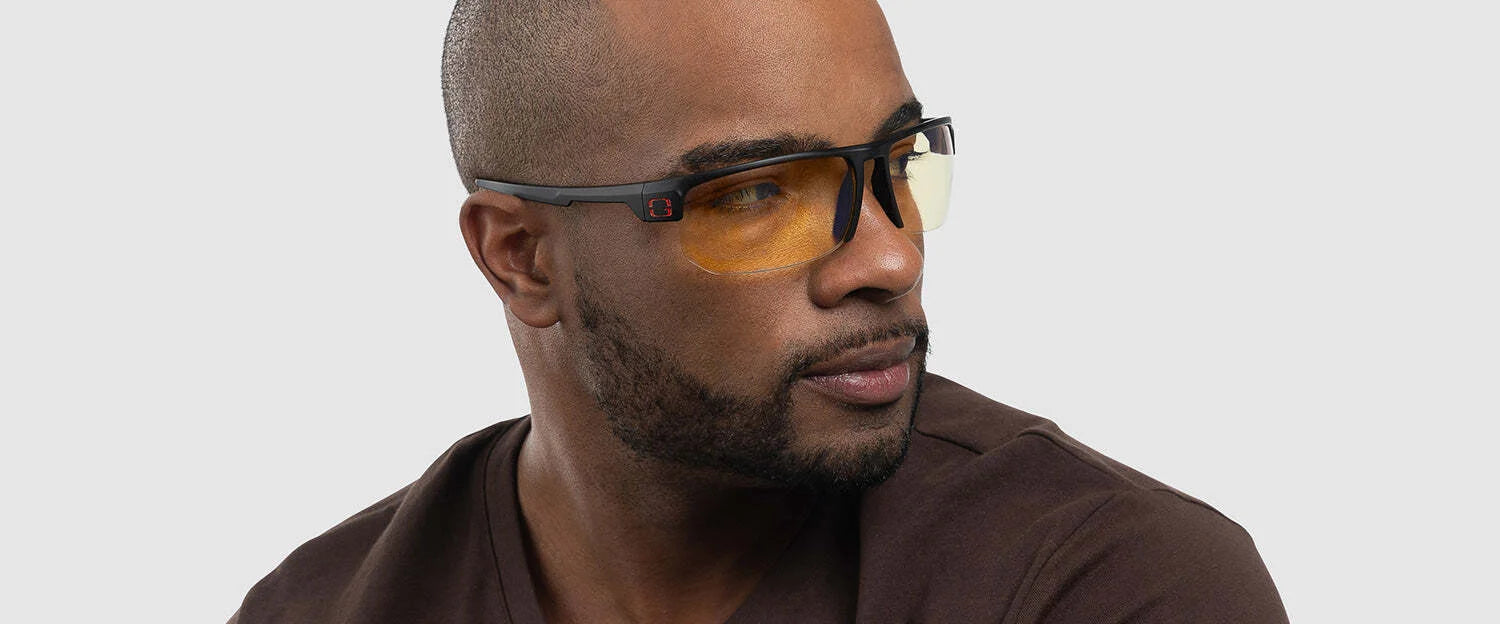 A man wearing Gunnar Torpedo 360 Computer Glasses with amber-tinted lenses and a brown shirt gazes to the side against a neutral background.