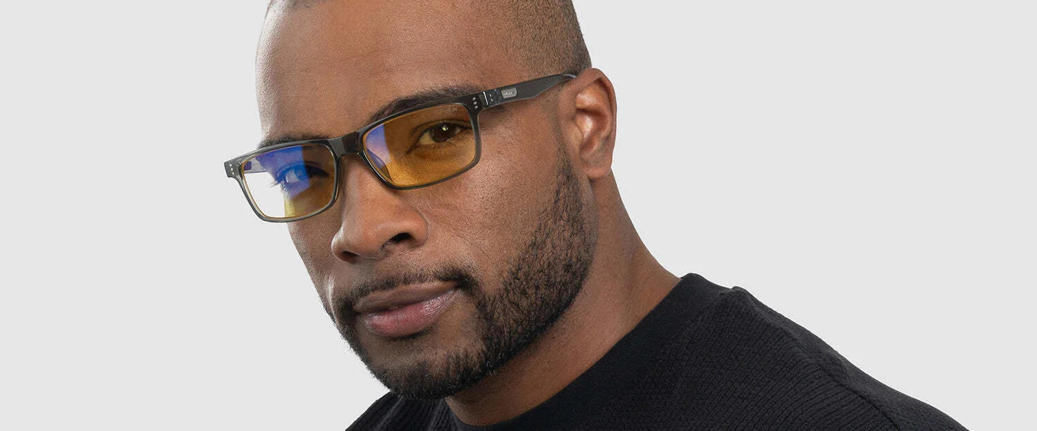 A man confidently looks at the camera wearing Gunnar Vertex Computer Glasses, featuring a durable nylon frame and blue light protection, against a white background.