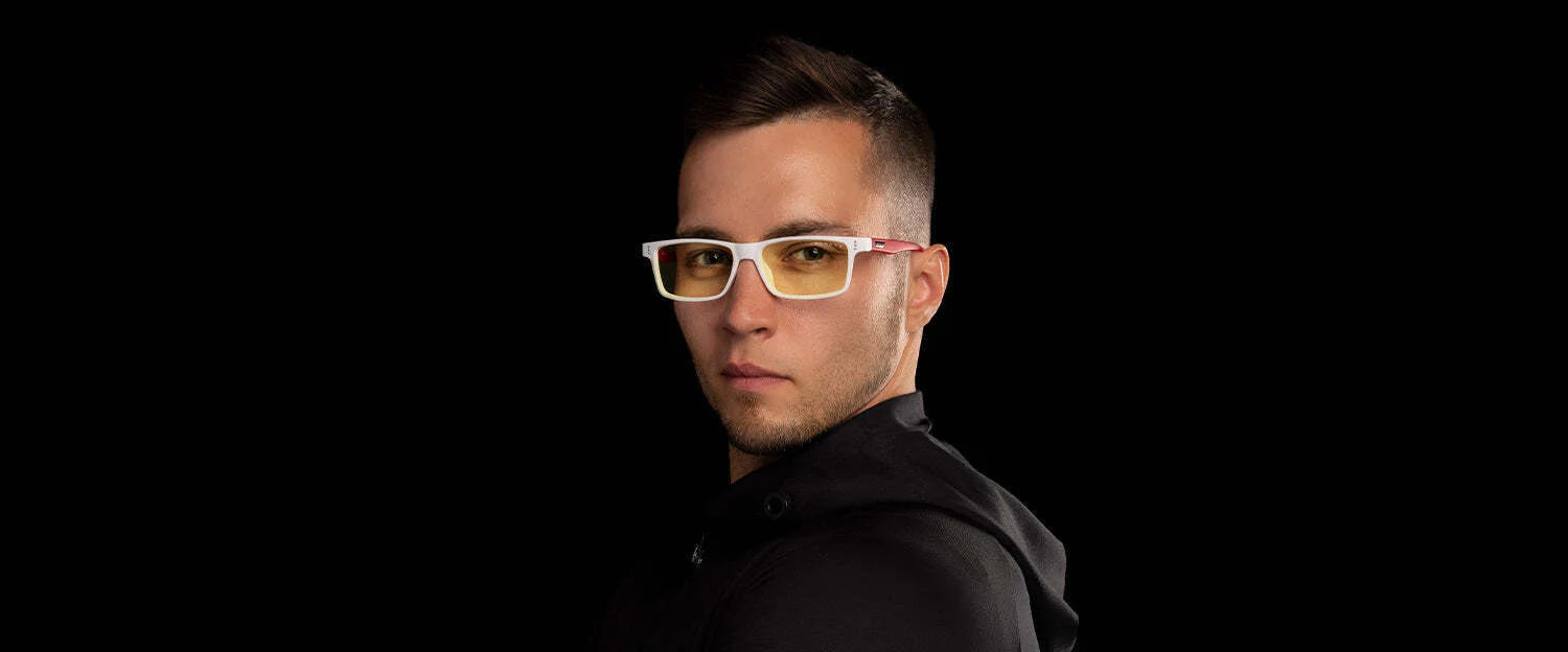 A person with short hair wears Gunnar Vertex St. Jude Computer Glasses, size 55, with yellow-tinted blue light protection and a black hoodie, set against a black background.