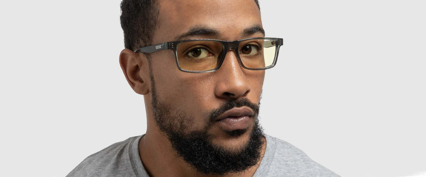 A man with a beard wearing Gunnar Vertex Computer Reading Glasses with yellow-tinted lenses and a gray shirt, standing against a light gray background.