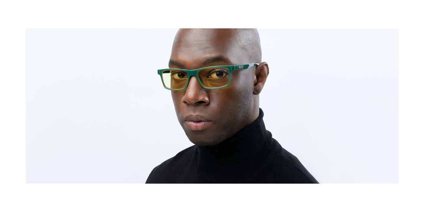 A man wearing Gunnar Vertex Computer Glasses with green frames and UV protection, paired with a black turtleneck, looks directly at the camera with a neutral expression.