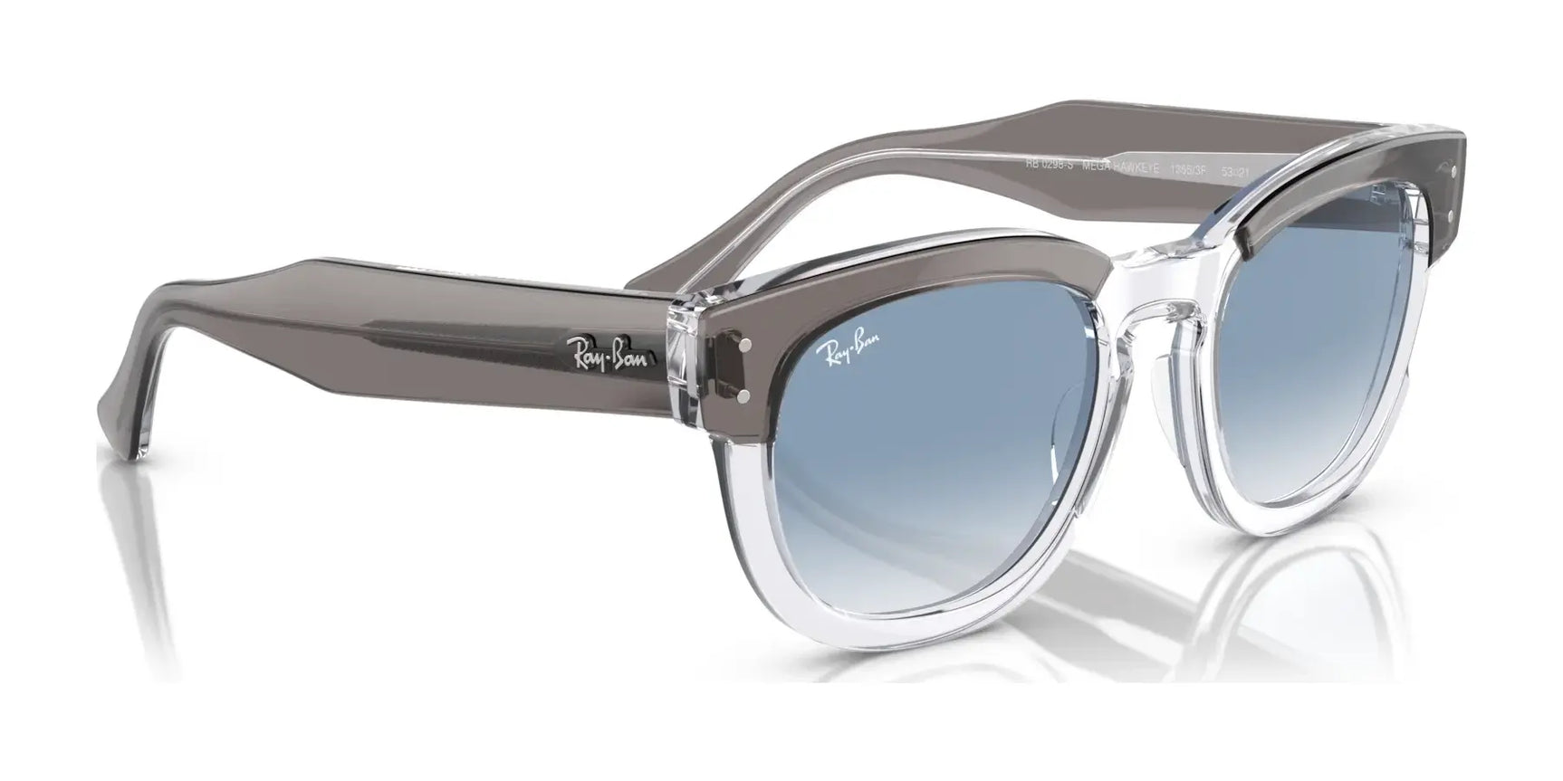 The Ray-Ban MEGA HAWKEYE RB0298S Sunglasses, size 53, feature clear acetate frames with a keyhole bridge and gray temples. Elegantly displayed on a reflective surface, these sunglasses showcase striking blue lenses.