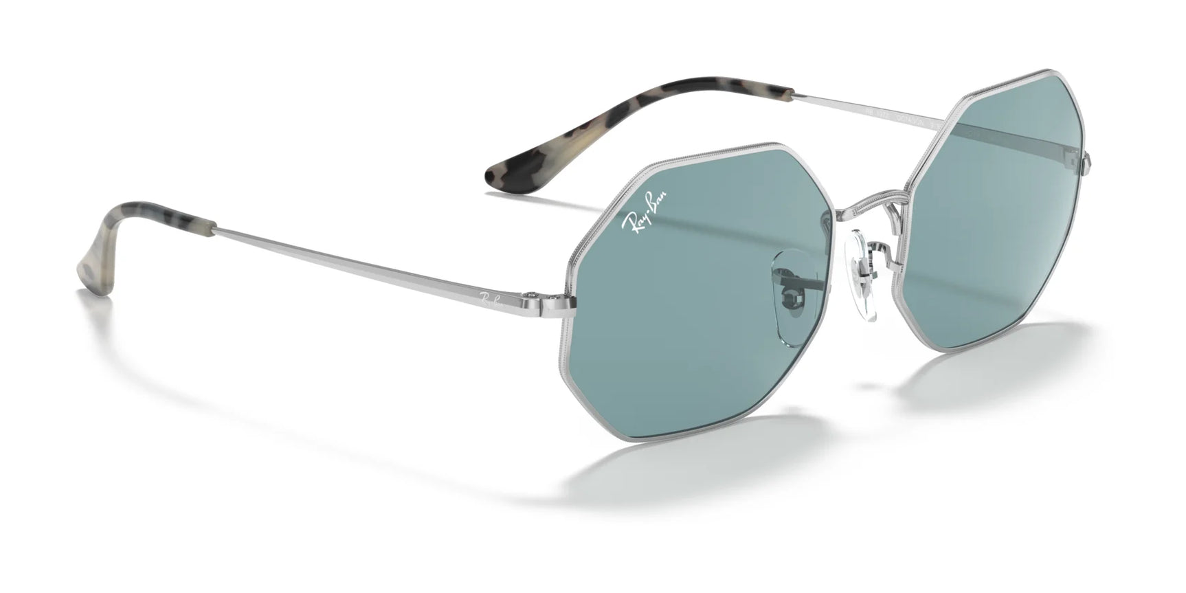 Protect your eyes in style with Ray-Ban OCTAGON RB1972 Sunglasses. These hexagonal frames, sized 54, feature sleek geometric silver metal and vibrant blue lenses, delivering a modern aesthetic for fans of unique style.