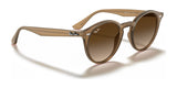 Ray-Ban RB2180F Sunglasses in brown with gradient lenses, reflecting iconic style and UV protection, rest on a white surface.