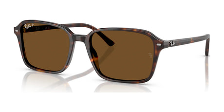 Ray-Ban RAIMOND RB2231 sunglasses feature tortoiseshell frames, brown polarized lenses, and a branded logo on the temples, exuding contemporary coolness as they rest on a reflective surface.