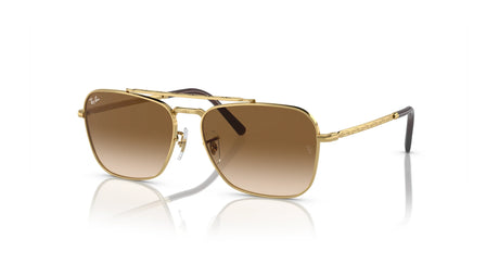 Ray-Ban NEW CARAVAN RB3636 sunglasses with gold frames and brown gradient lenses glimmer on a reflective surface, highlighting their premium design.