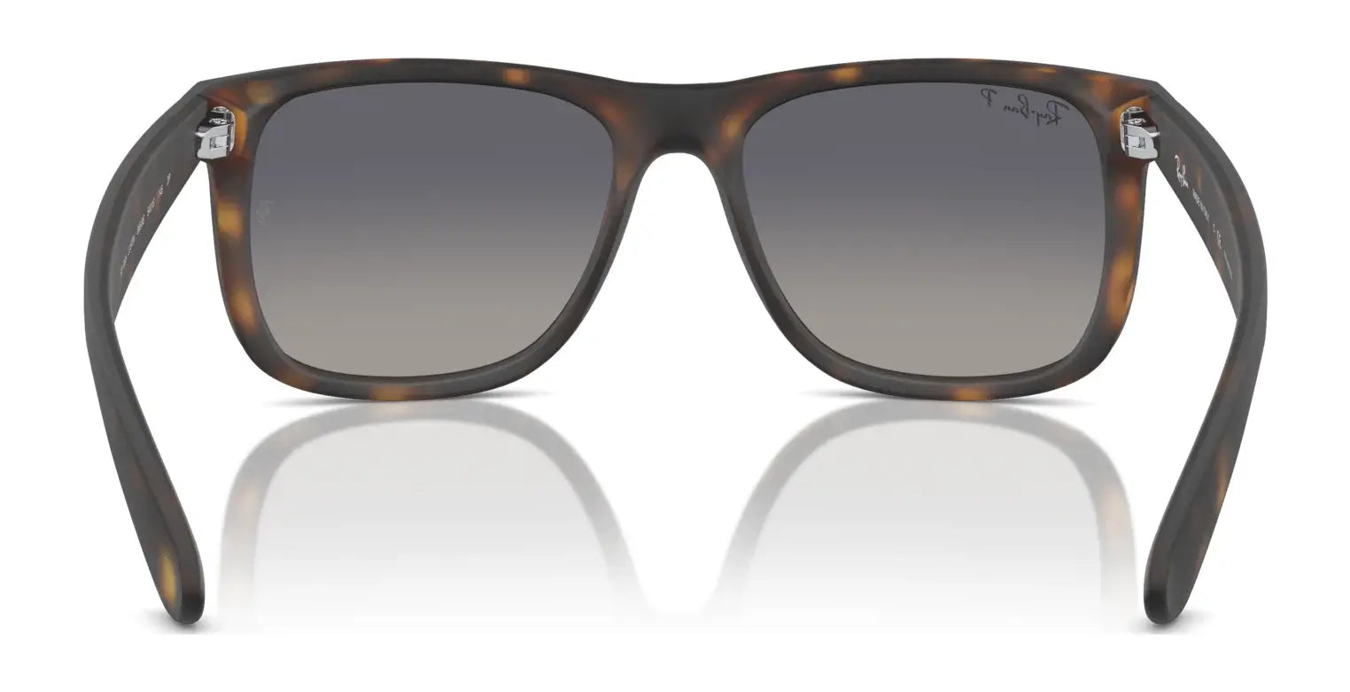 The Ray-Ban JUSTIN RB4165 tortoiseshell square sunglasses with gray gradient lenses offer 100% UV protection, elegantly displayed on a reflective surface.