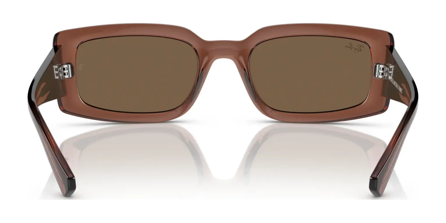 The Ray-Ban KILIANE RB4395 Sunglasses, in a rectangular brown design, are crafted from bio-based acetate and reflected on a glossy white surface. These Size 54 sunglasses offer stylish UV protection for any occasion.