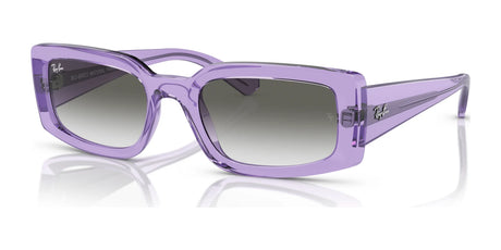 The Ray-Ban KILIANE RB4395 sunglasses, size 54, with transparent violet bio-based acetate square frames and UV-protective tinted lenses, rest elegantly on a reflective surface.