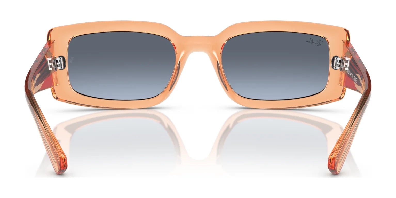 The Ray-Ban KILIANE RB4395 Sunglasses, Size 54, feature rectangular frames in vibrant orange bio-based acetate. The dark gradient lenses offer a mysterious touch and essential UV protection, all elegantly reflected on a sleek white surface.