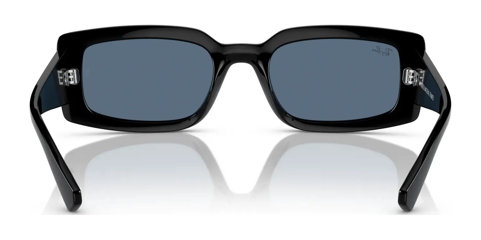 Front view of Ray-Ban KILIANE RB4395F Sunglasses, black with square frames and dark lenses, resting on a reflective surface, showcasing luxurious style.