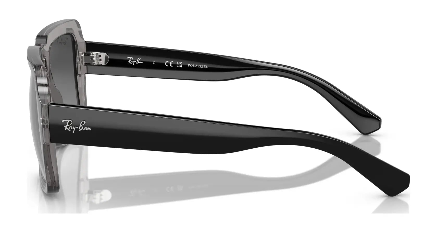 Side view of black Ray-Ban MAGELLAN RB4408 Sunglasses with clear lenses and UV protection, made from bio-based acetate. The Ray-Ban branding adorns the temples as they lay on a reflective surface.