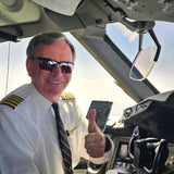 Smiling pilot wearing Scheyden CIA GRABBER Sunglasses in size 65 and a captain's uniform gives a thumbs up in the cockpit of an aircraft.