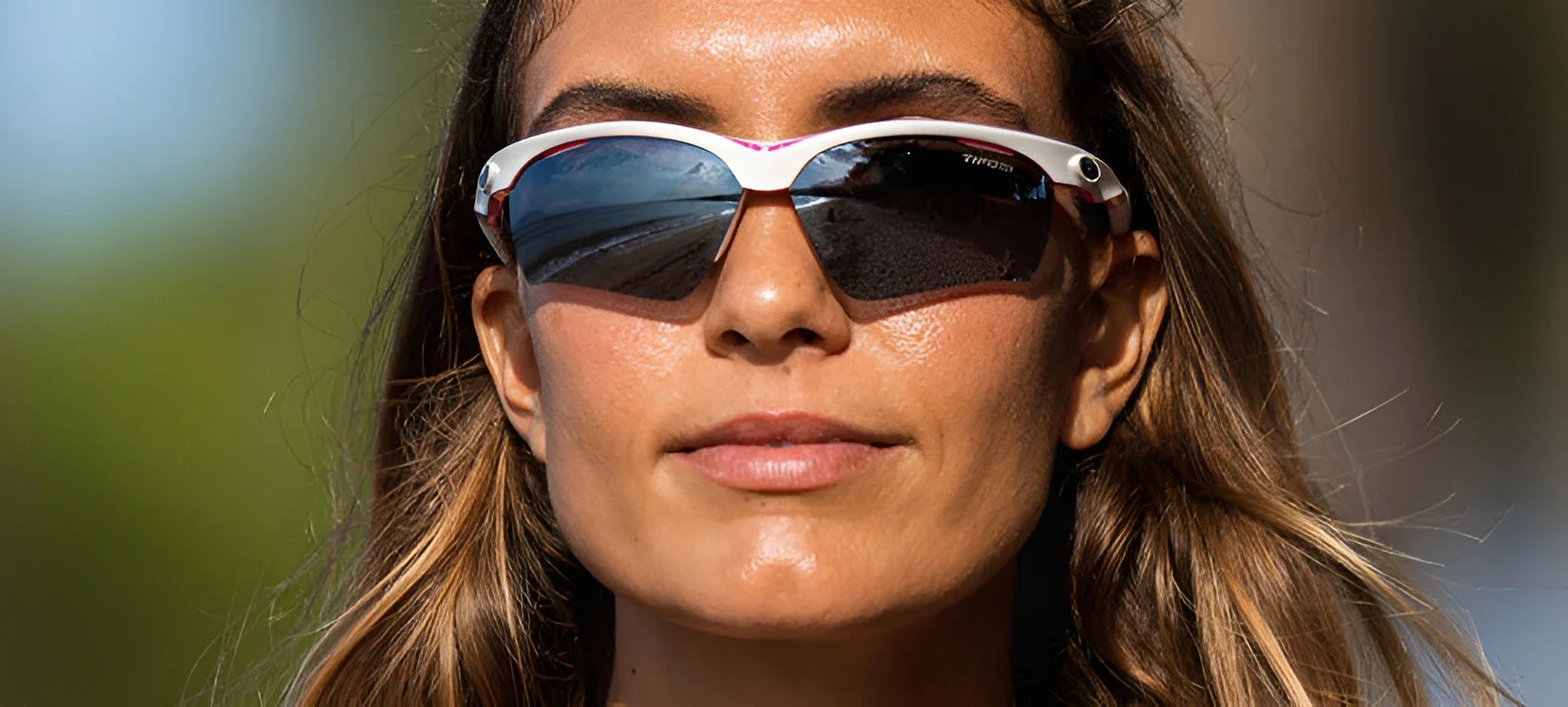 A woman with long brown hair gazes ahead in a sunny setting wearing white Tifosi Optics VERO Sunglasses, ideal for smaller faces and multi-sport activities.