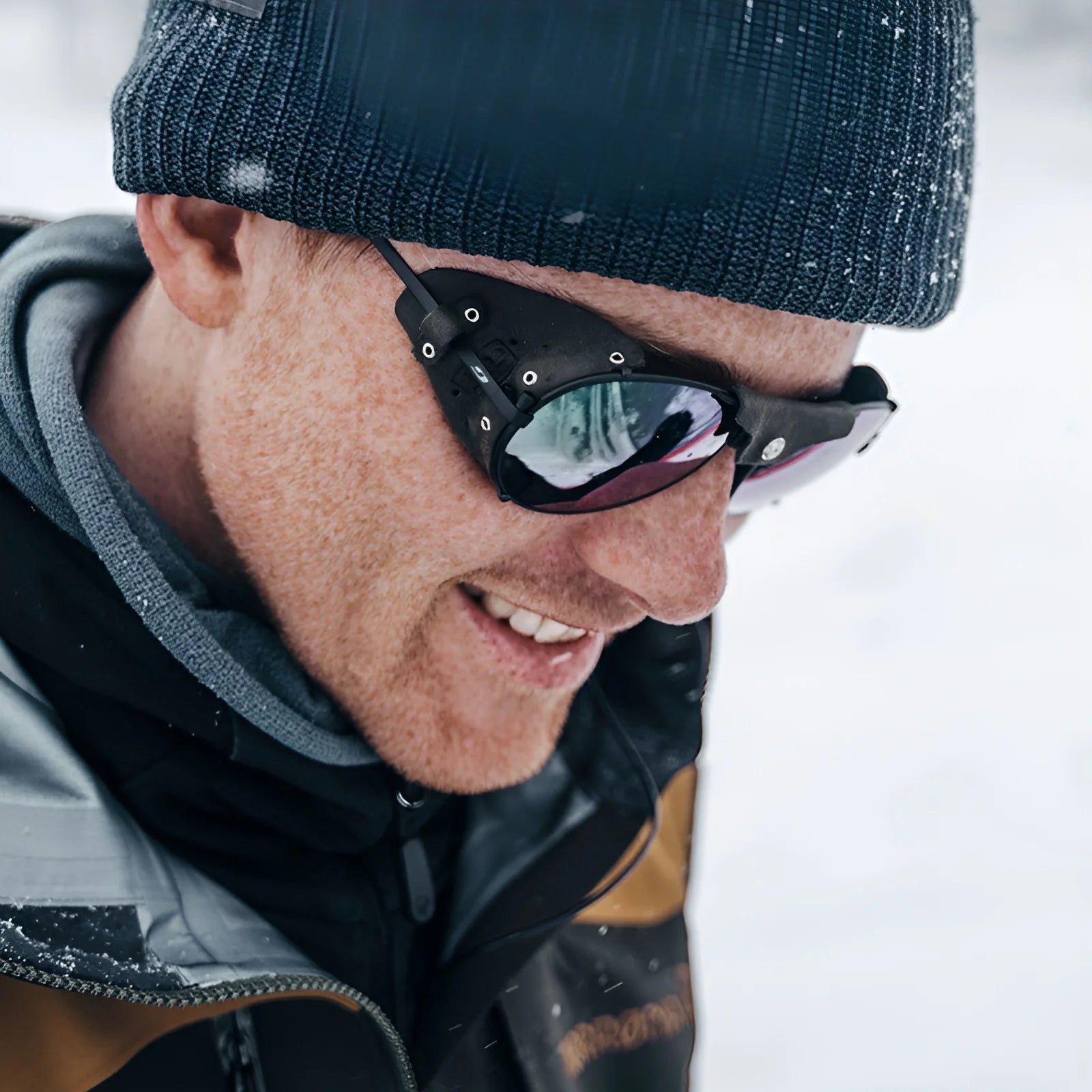 A person in winter clothing, smiling in a snowy setting, wears Julbo Cham Sunglasses Size 58.