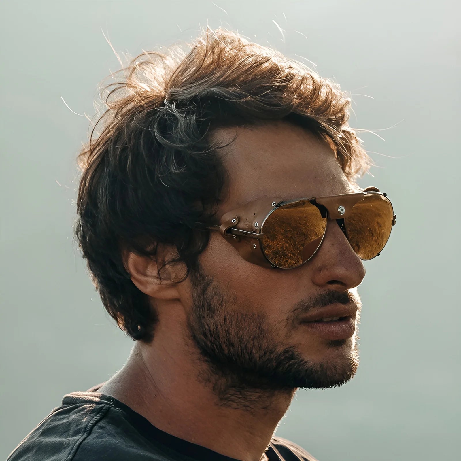 A man with tousled hair wearing Julbo Cham Sunglasses (Size 58) gazes to the side against a hazy background.