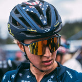 The cyclist, wearing a star-patterned helmet, sported Julbo Edge Sunglasses by Julbo with reflective lenses and anti-fog coating, exuding focus and determination during the race.