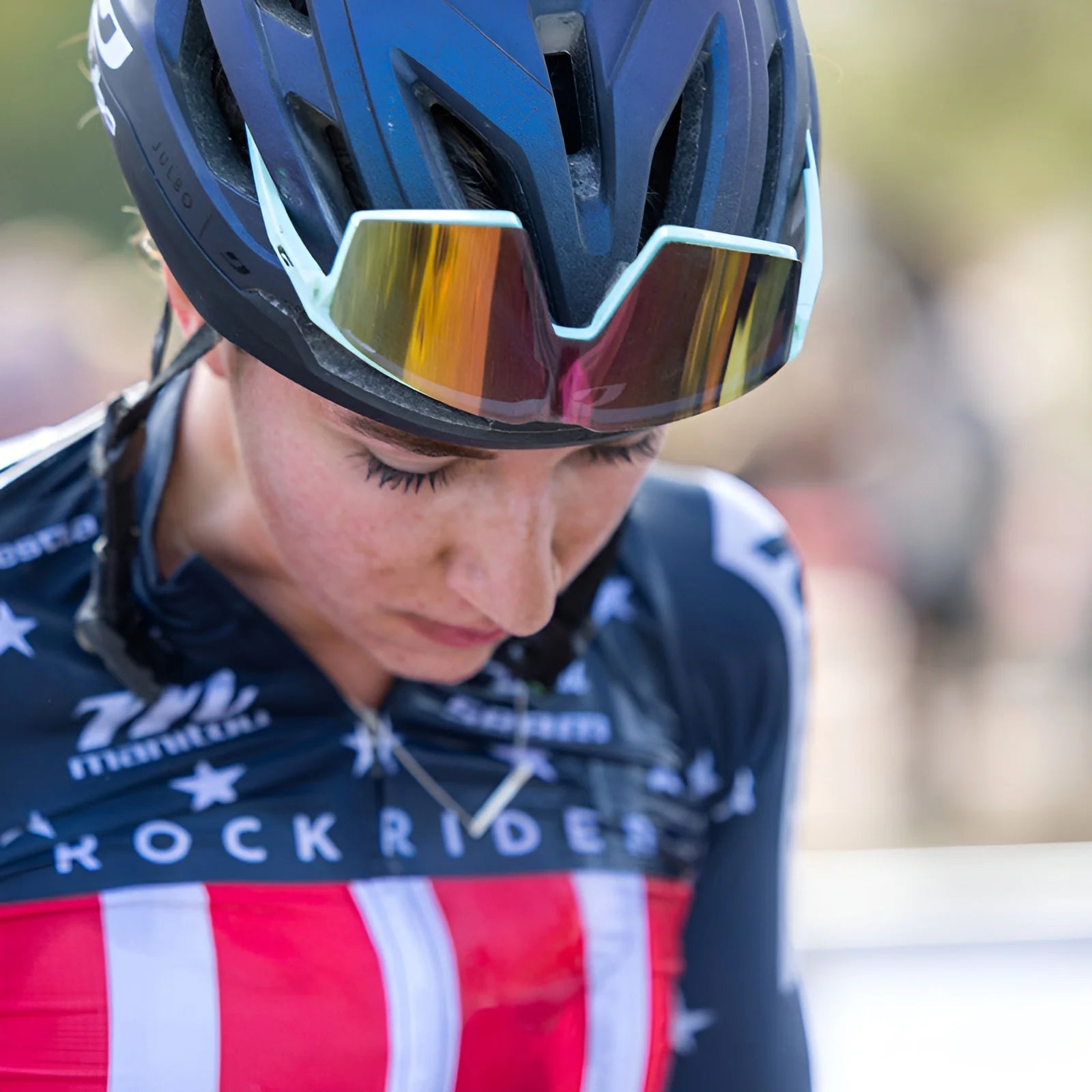 A cyclist wearing Julbo Edge Sunglasses with a helmet and a star-spangled jersey looks down.