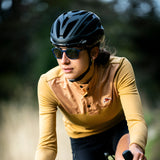 A cyclist, sporting Julbo Slack Sunglasses and a yellow jersey with a helmet, rides outdoors, effortlessly merging performance and style.