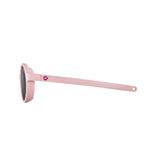 The Julbo Walk Sunglasses in Size 39 are stylish pink kids' sunglasses with round frames and a small lip icon on the arms, viewed from the side. Crafted for durability, they blend style and resilience perfectly.